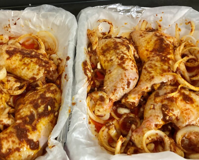 2 oven pans with onions and chicken in sauce