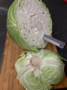 Cutting off 1/4 of large cabbage, near the end of the stem, before parboiling and detaching leaves, in preparation for stuffing